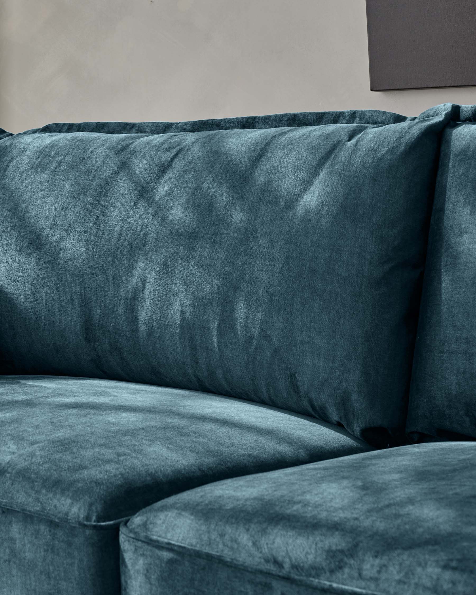 Luxurious deep-blue velvet sofa with plush backrest and seating cushions, demonstrating an inviting texture and exemplary comfort.