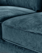 Close-up of a luxurious navy blue velvet sofa displaying smooth fabric texture, plush seating cushions, and comfortable backrest.