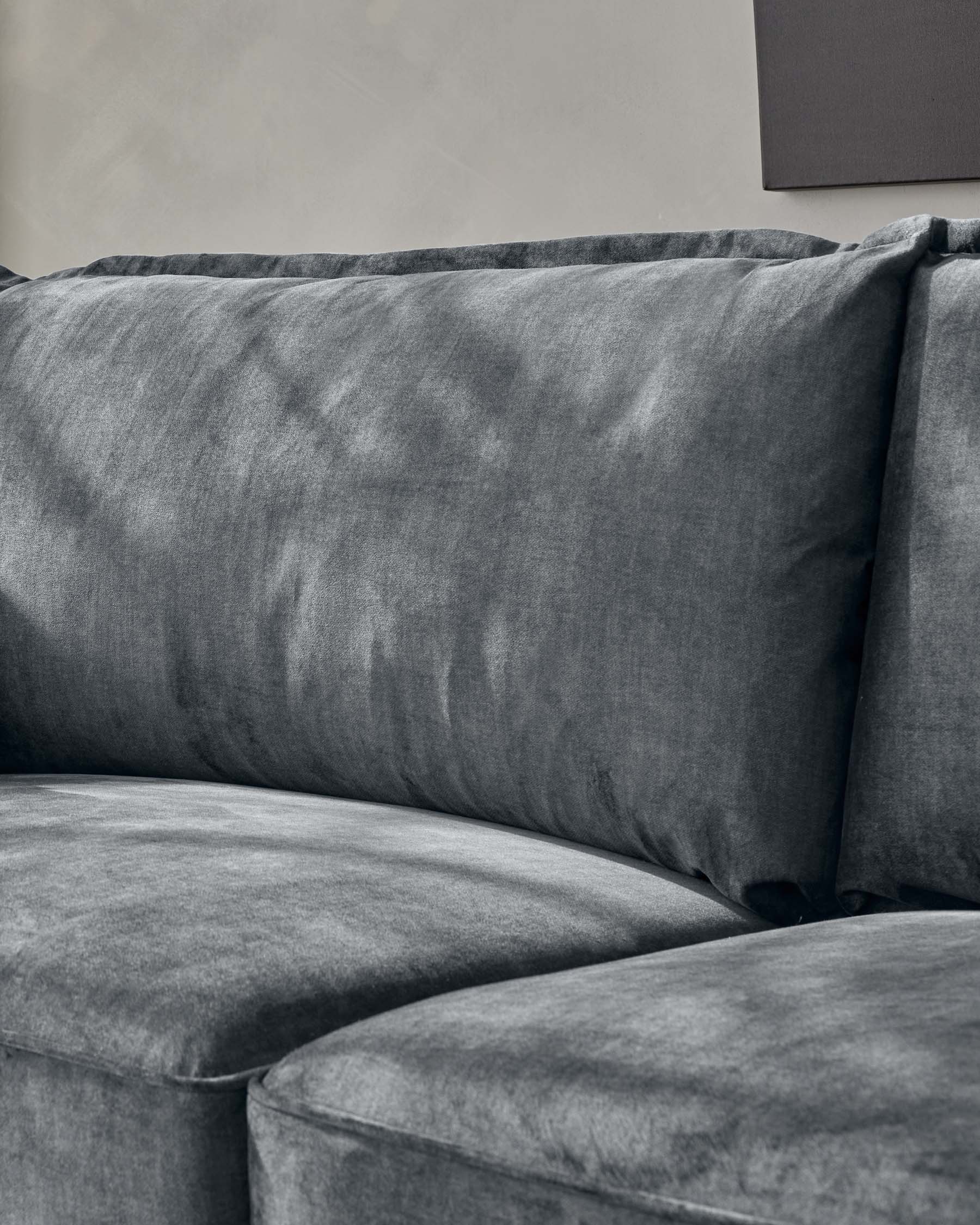 Close-up of a plush charcoal grey velvet sofa showcasing its soft texture and deep cushioning.