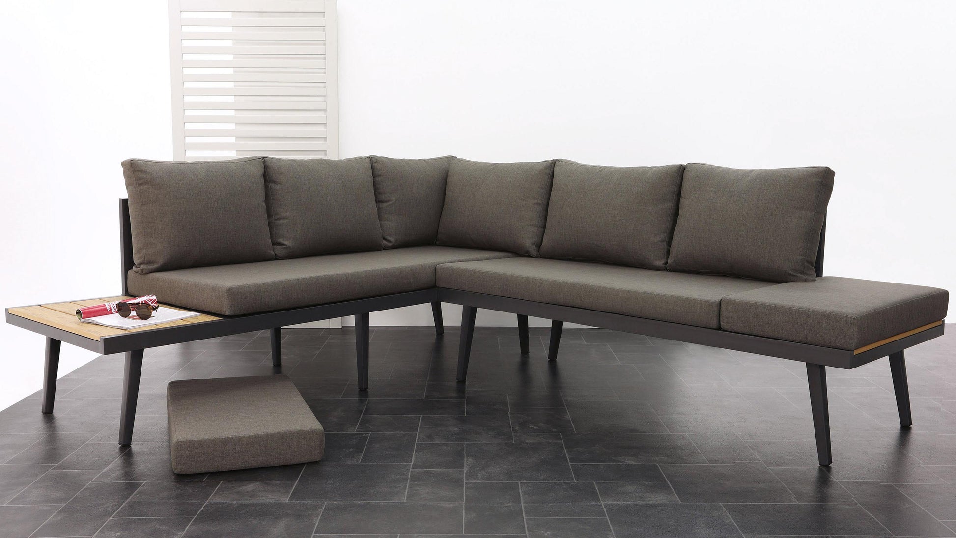 Modern L-shaped sectional sofa in dark grey fabric with black metal legs, paired with a matching rectangular ottoman and a wood-topped coffee table with black metal frame.