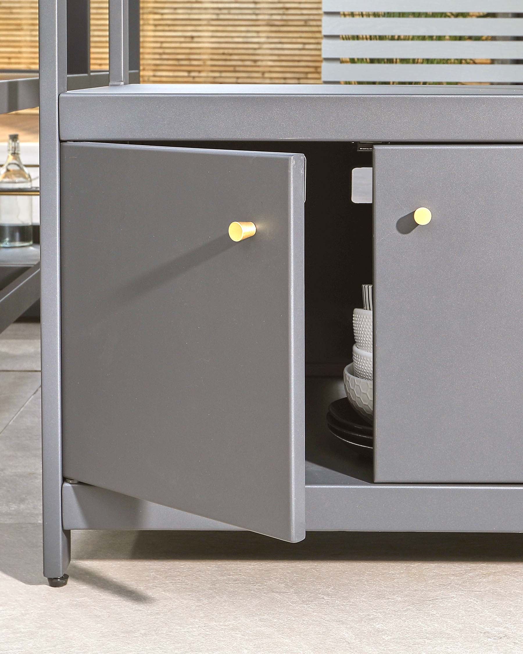 Sleek gray cabinet with gold knobs, featuring open and closed storage showcasing decorative plates and kitchen items.