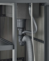 No furniture is visible in the image; it displays a close-up of grey and black piping infrastructure, possibly under a sink or behind an appliance, with no furniture evident.