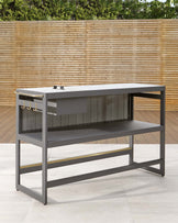 Modern outdoor charcoal grill table with a sleek, dark grey metal frame, featuring a sturdy tabletop, a spacious lower shelf, and hanging hooks on one side for grilling utensils, set against a natural bamboo fence backdrop.