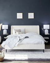 Stylish bed with plush upholstery, accompanied by sleek bedside tables, modern lamps, and cozy decorative elements.