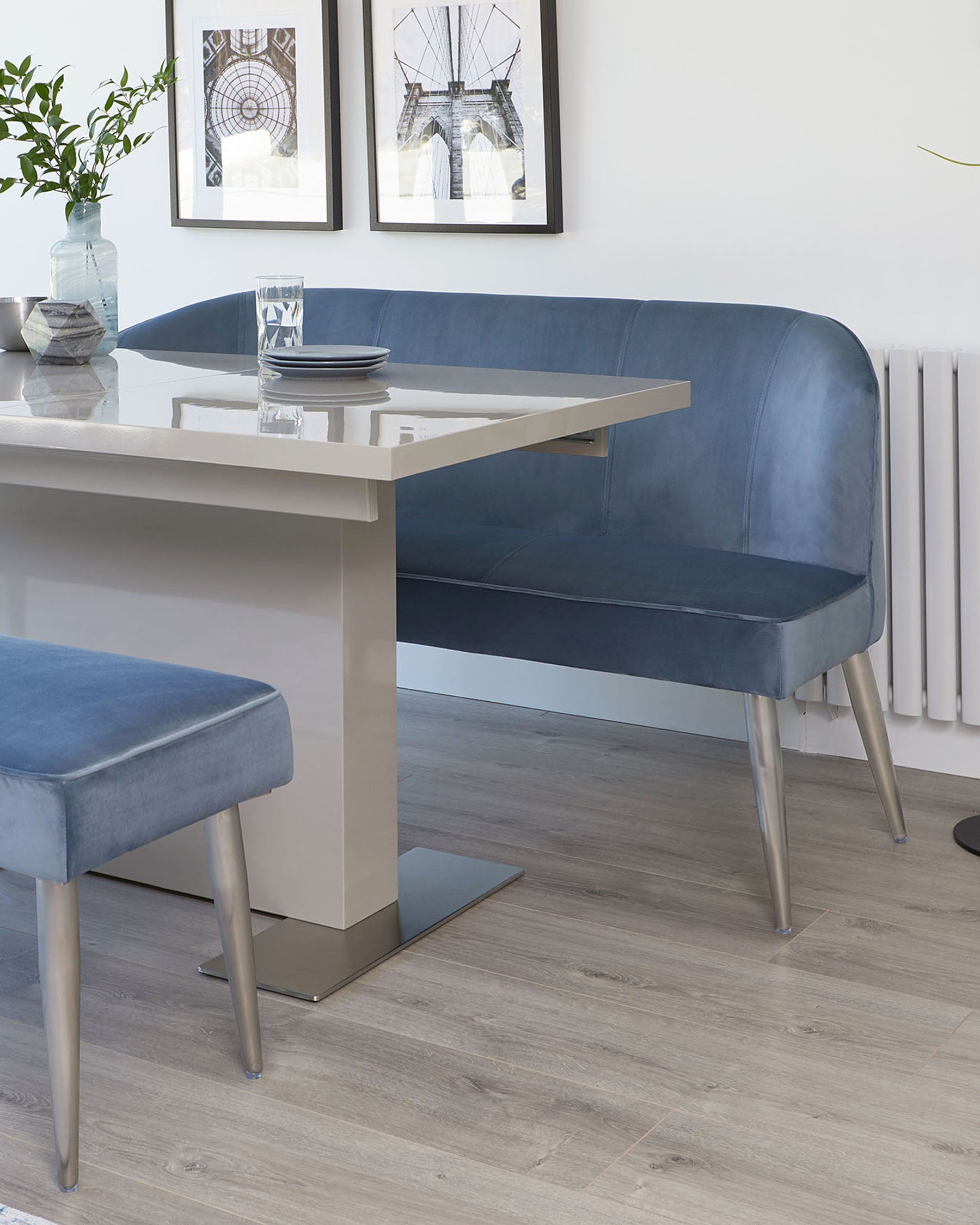 Modern dining room furniture set featuring a sleek white rectangular table with a glossy finish and metallic base, accompanied by a blue upholstered bench with backrest and a matching stool with metallic legs.