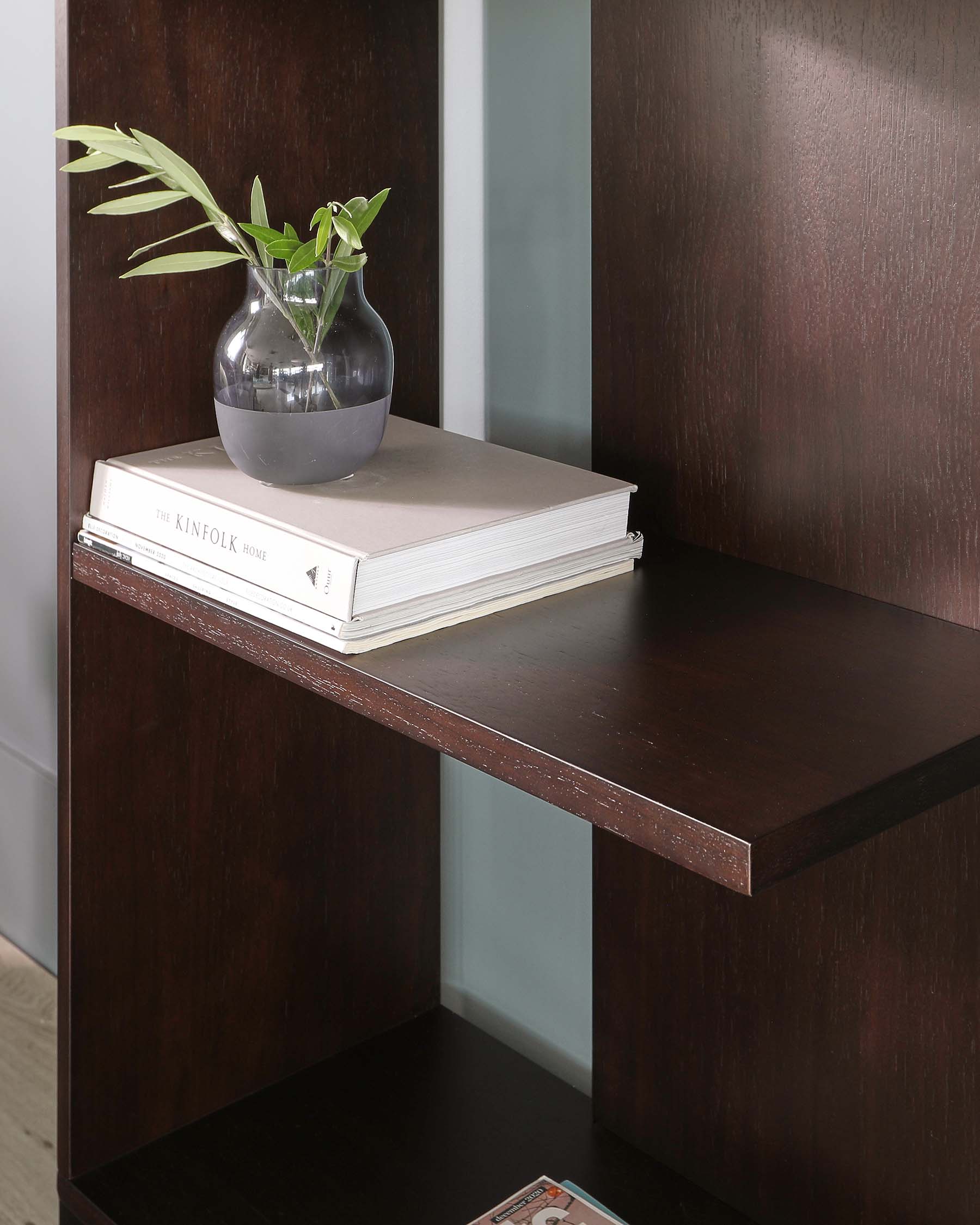 Contemporary dark wood console table with a smooth finish and a minimalist design featuring a rectangular tabletop and a flat side support, with a clear vase and books on the surface.