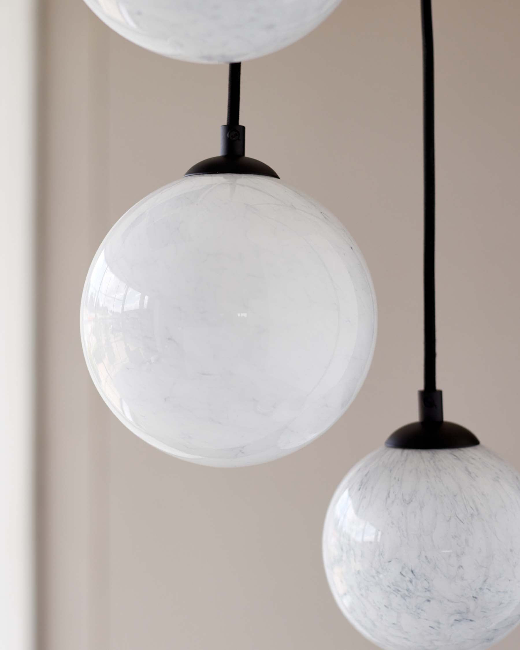 Modern pendant lights with marbled white glass spheres and matte black fixtures.