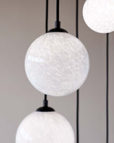 Elegant spherical pendant lights with white textured glass shades and matte black fittings.