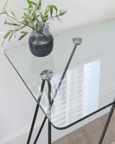 Modern glass-top table with a minimalist, black metal frame.