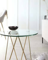 Contemporary round glass-top side table with slender gold-finished metal legs.