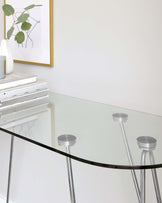 Modern minimalist glass-top table with sleek metal legs visible through the clear surface, providing a contemporary look for any interior space.