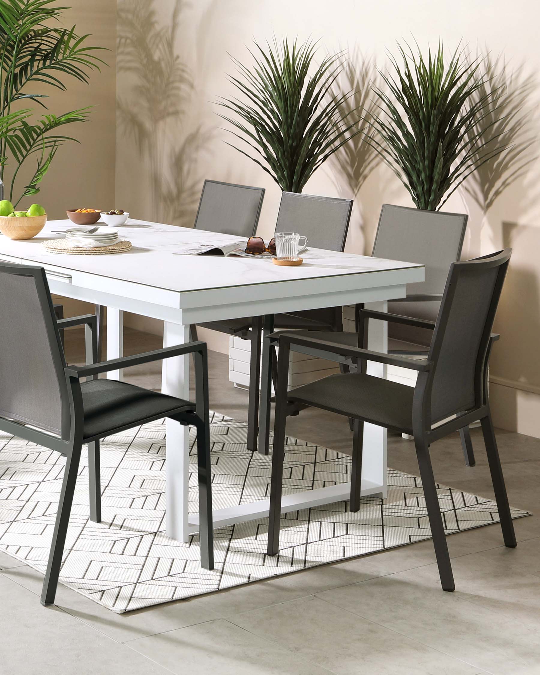 Modern dining set featuring a white rectangular table with a sleek finish and four contemporary dark chairs with textile seating and backing, set on a geometric-patterned area rug.