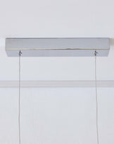 Modern minimalist wall-mounted picture light in a matte silver finish with two adjustable cords hanging down against a white wall background.