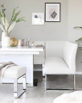 Sleek white upholstered bench and stool with chrome legs, paired with a glossy table, complemented by decorative accents.