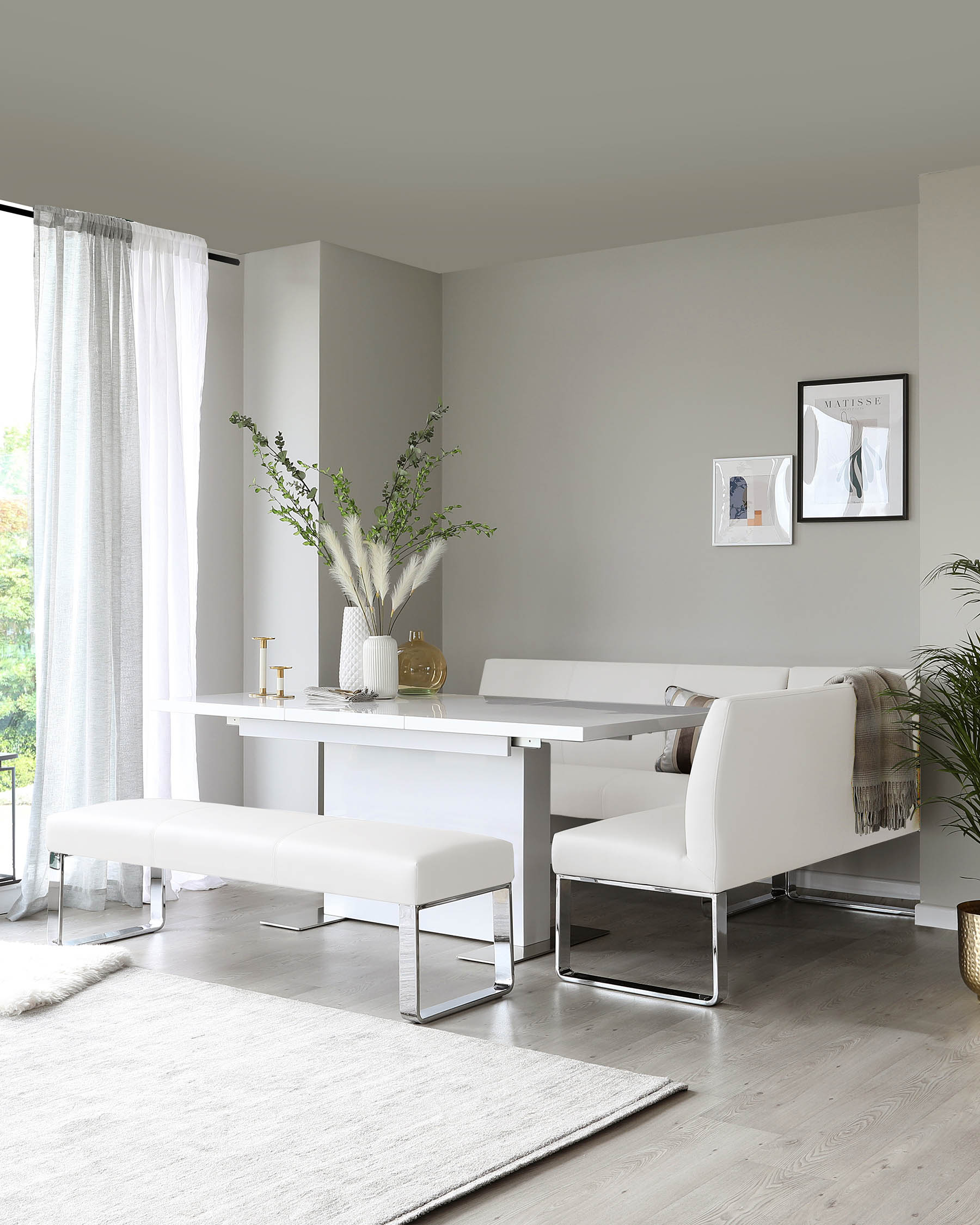 Modern minimalist dining room furniture set in a clean, contemporary design, featuring a sleek white dining table with a thick rectangular top supported by a sturdy flat side panel leg, and paired with two white upholstered benches with cushioned seats and shiny chrome frames, complemented by a matching white upholstered armchair with chrome legs at the end of the table.