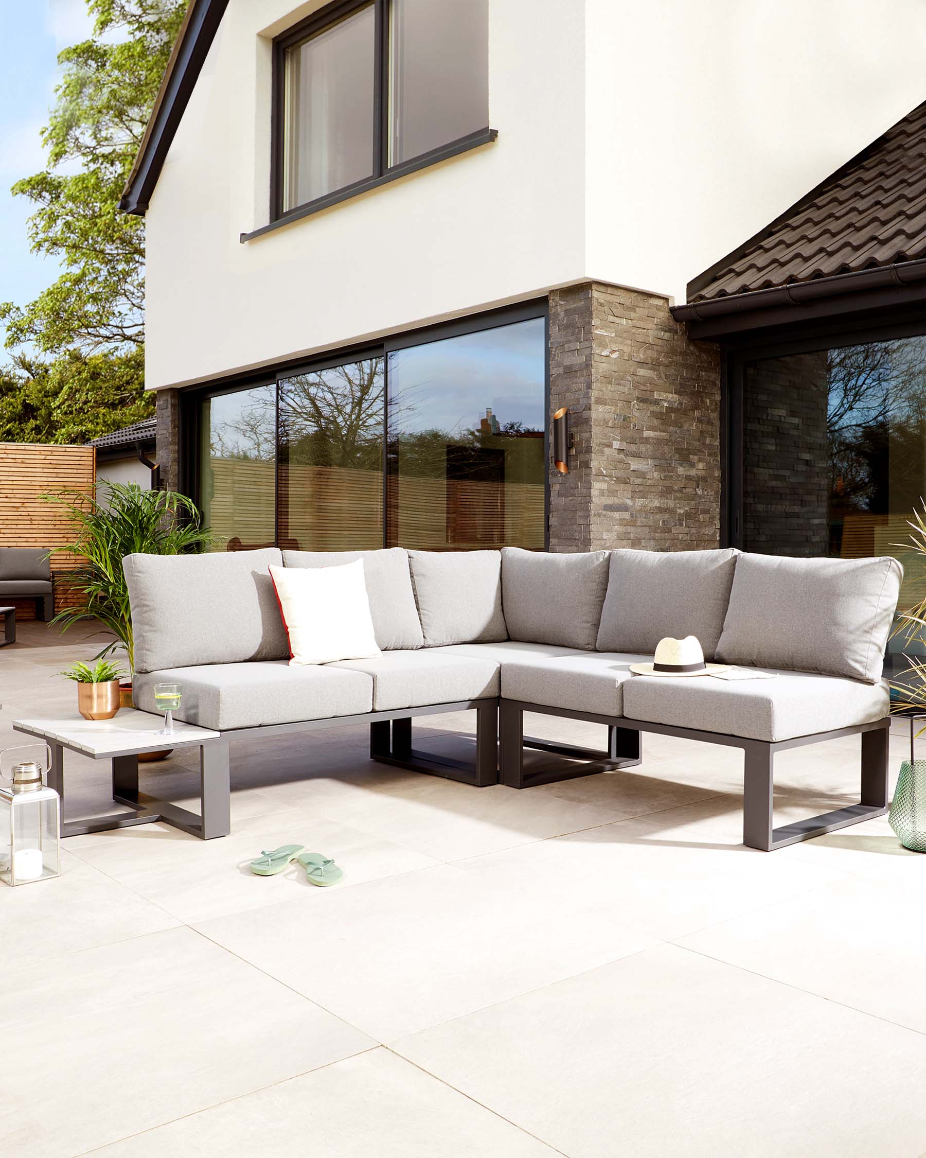 Contemporary outdoor sectional sofa with light grey cushions on a sleek, dark-framed base, paired with a matching low-profile rectangular coffee table.