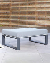 Modern rectangular ottoman with grey upholstery and black metal base.