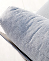 Close-up of a textured light grey cushion, possibly part of an outdoor lounge chair or sofa, with a sleek black frame visible beneath it.