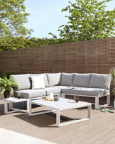 Modern outdoor furniture set consisting of an L-shaped sectional sofa with light grey cushions and a rectangular, white low-profile coffee table with slatted top design.