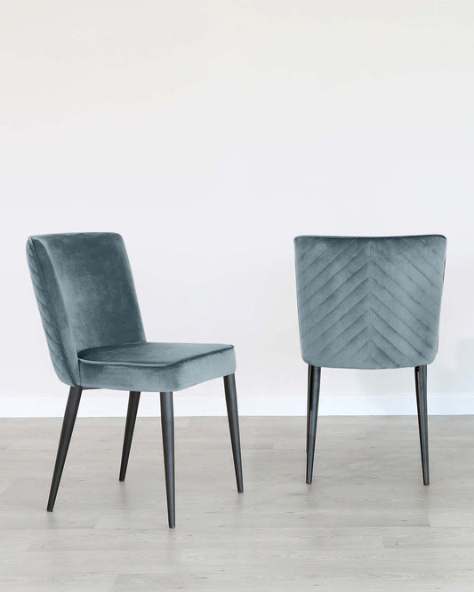 Two modern velvet dining chairs with black metal legs, one with a smooth seat and curved backrest, and the other with a chevron-patterned backrest, on a light wooden floor against a white wall.