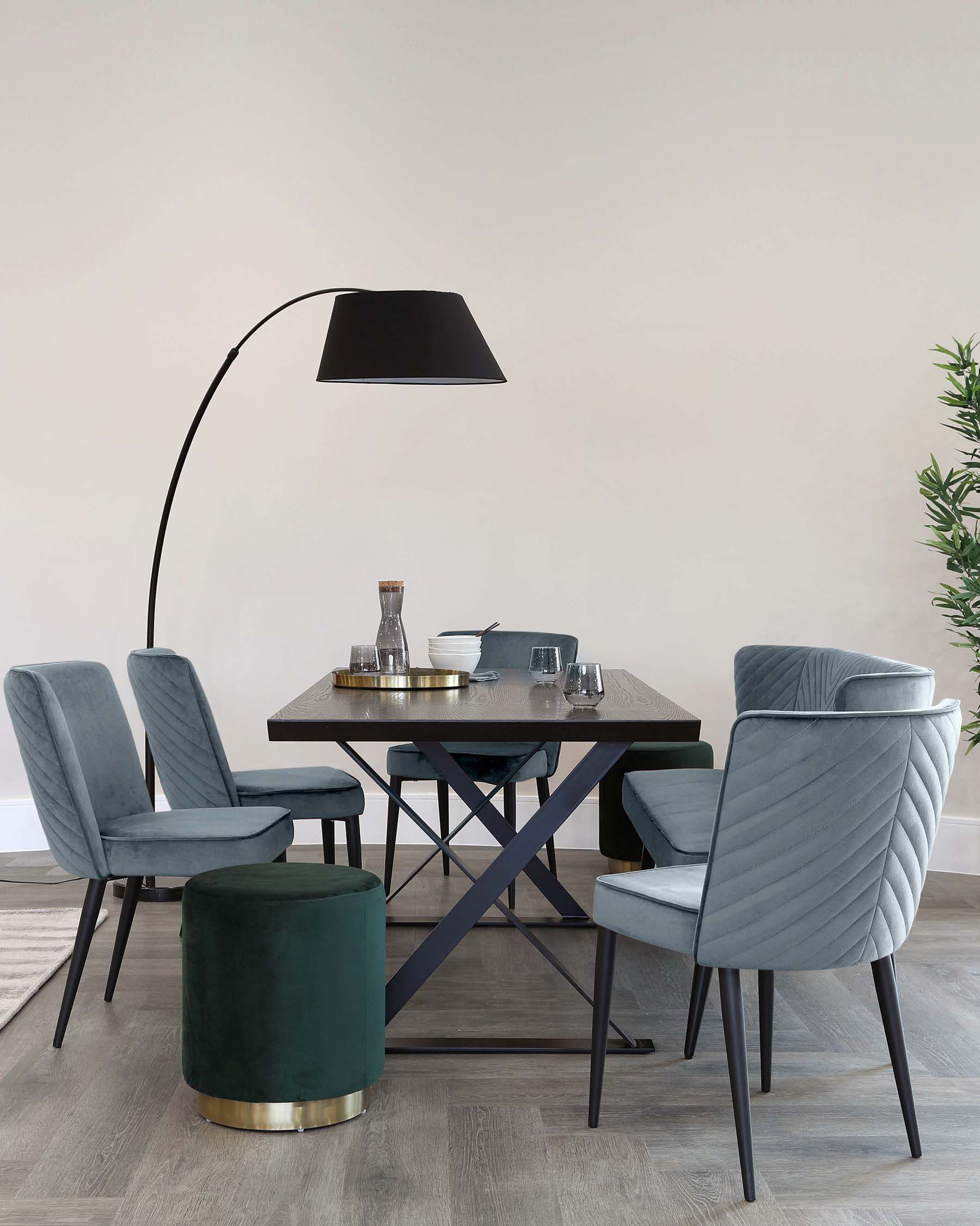 A modern dining set featuring a rectangular table, plush velvet chairs with quilted backs, a round stool, and a stylish floor lamp.