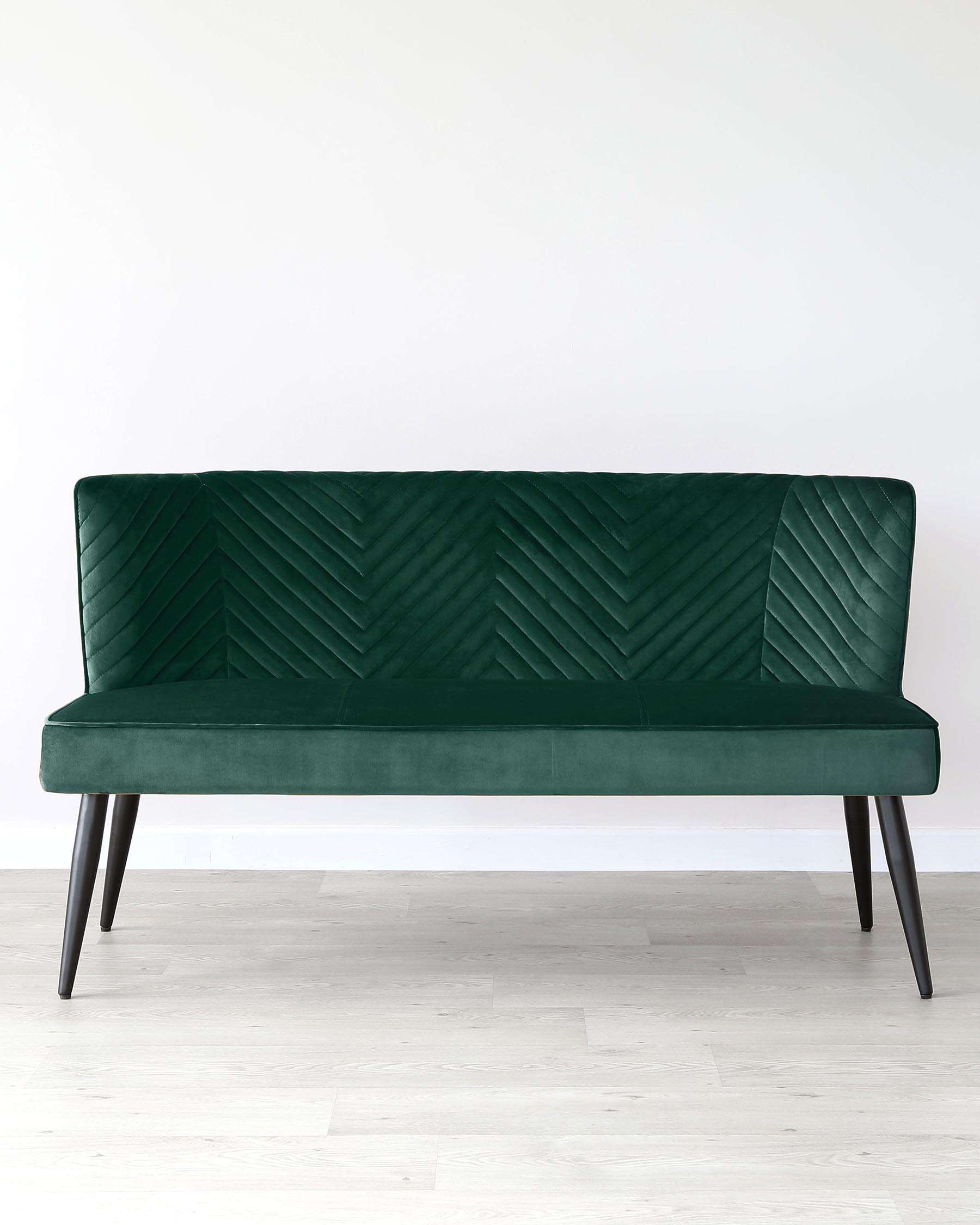 Elegant emerald green velvet sofa with a distinctive geometric chevron pattern on the backrest, featuring a sleek silhouette with four slender, black tapered legs.