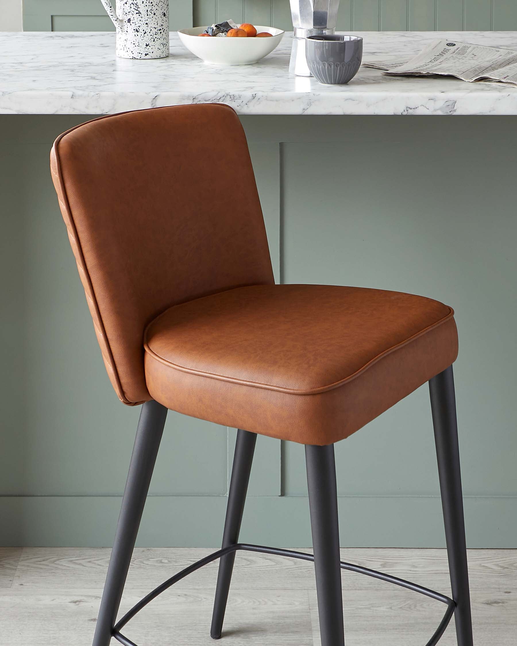 Modern counter-height bar stool with a brown faux leather upholstered seat and backrest, featuring black metal legs with a footrest ring.