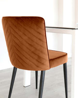 Modern dining chair with a caramel brown upholstered seat and quilted backrest, paired with black metal legs.