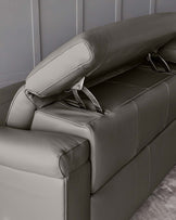 Contemporary grey leather sofa with an adjustable headrest and a sleek metal accent on the armrest.