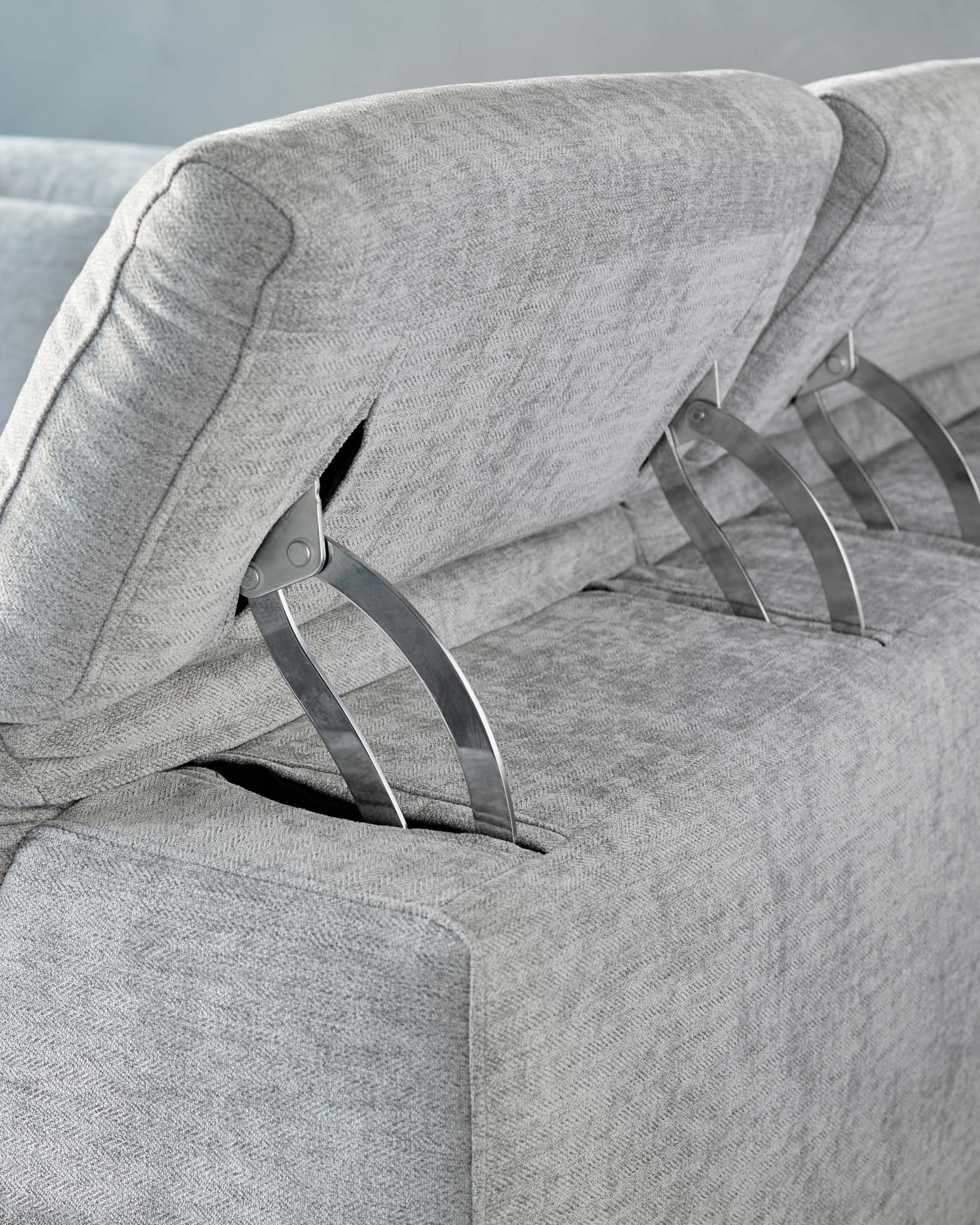 Contemporary light grey fabric sofa with a textured upholstery design and stainless steel legs showing a detail view of the armrest and cushioning.