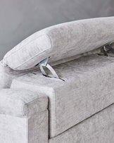 Elegant light grey textile sofa with a close-up on the adjustable headrest mechanism and armrest, showcasing modern design and functionality.