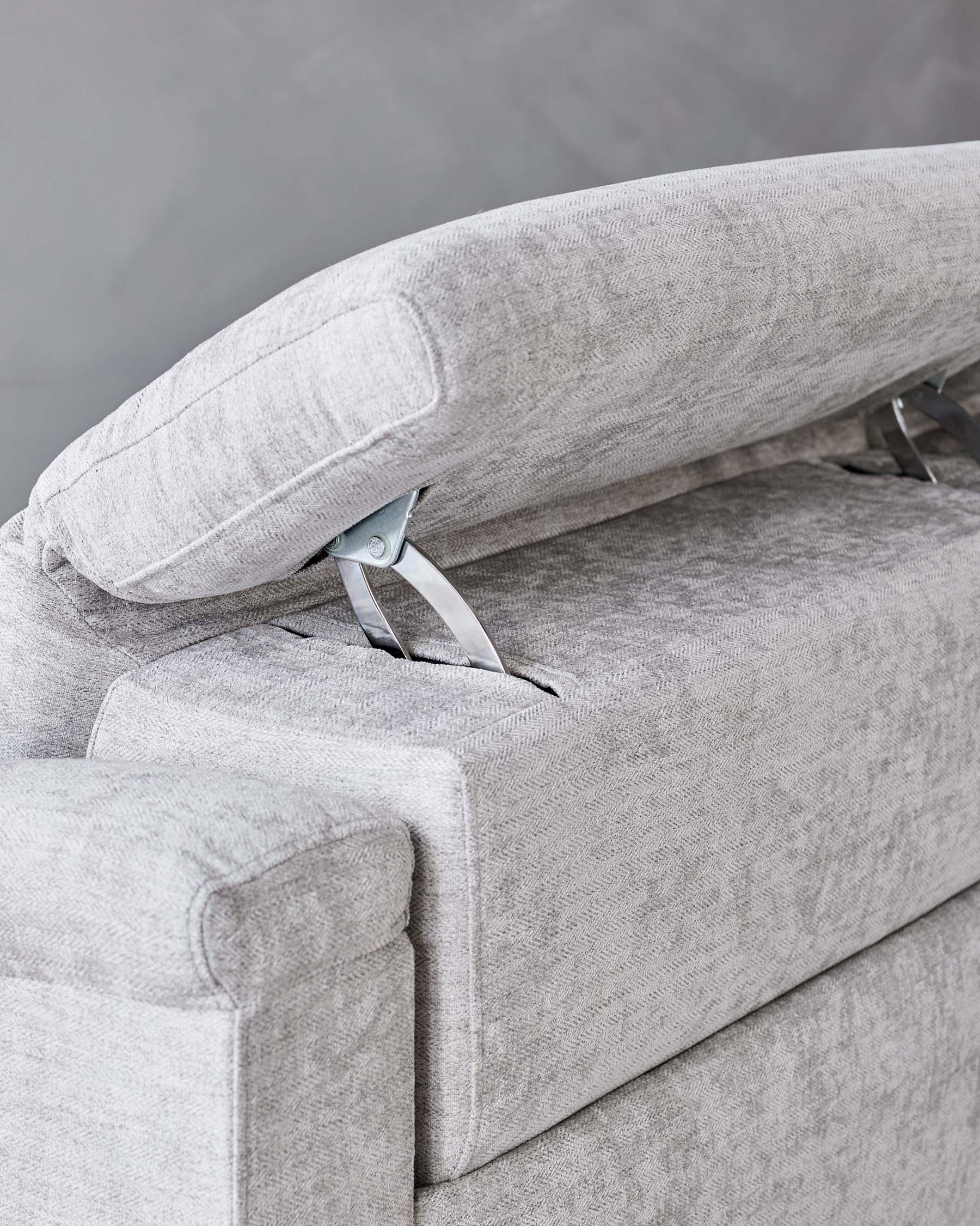 Elegant light grey textile sofa with a close-up on the adjustable headrest mechanism and armrest, showcasing modern design and functionality.