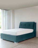 Contemporary teal upholstered platform bed with tufted headboard and white bedding, set against a light neutral-toned room with hardwood floors and sheer curtained window.