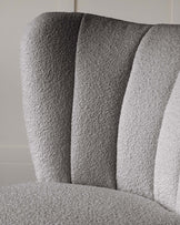 Close-up of a textured fabric upholstered chair in grayscale, featuring wide, vertical stripes in alternating shades.