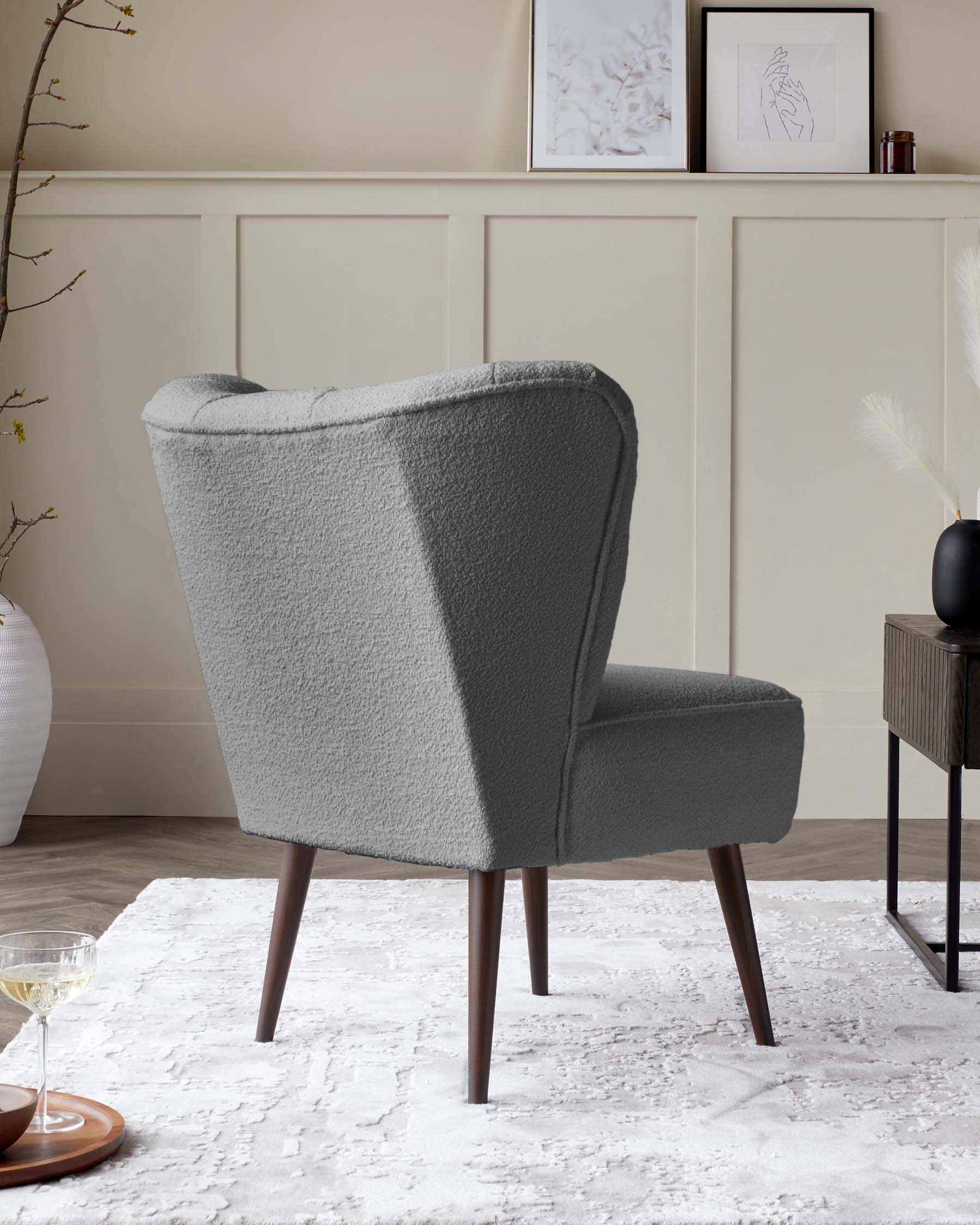 Elegant modern accent chair with a wingback design, upholstered in a textured grey fabric, featuring clean lines with a mid-height backrest, and angled dark wooden legs.