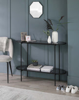 Elegant and contemporary semi-circular console table with a smooth black finish. The sleek design features a two-tiered structure; the upper level provides a display surface while the lower shelf offers additional storage space. Slim, straight legs support the table, creating a minimalist silhouette ideal for modern interiors.