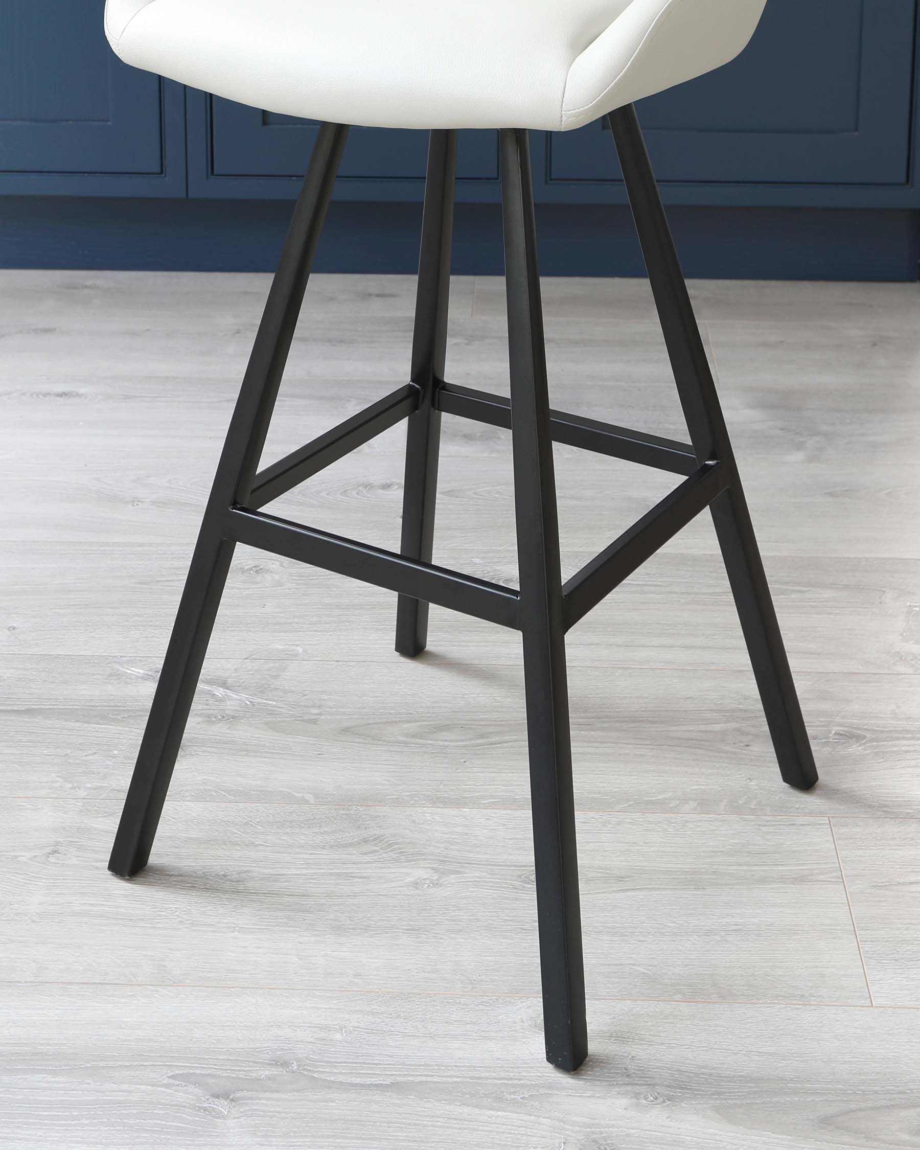 Modern bar stool with a sleek, matte black frame and a white cushioned seat, showcased against a herringbone-patterned light wooden floor and a blue wall.