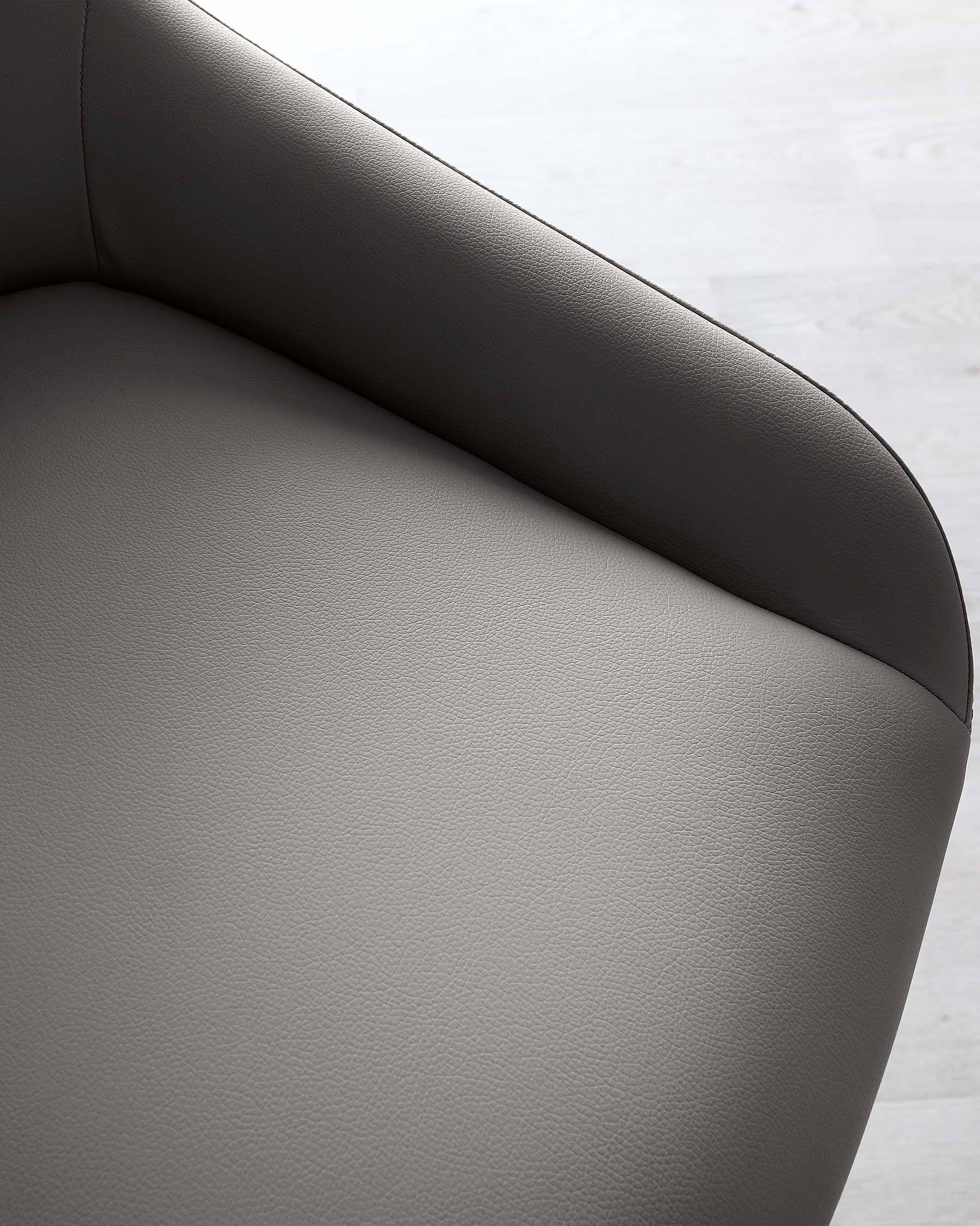 Close-up view of a modern chair featuring a curved backrest and seat with textured grey leather upholstery, set against a light hardwood floor.