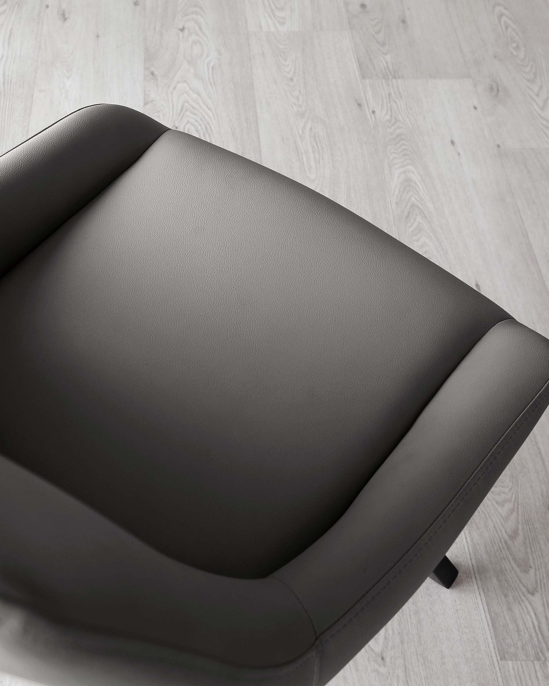 Modern black leather armchair with clean lines and a minimalist design, set on a light wooden floor.