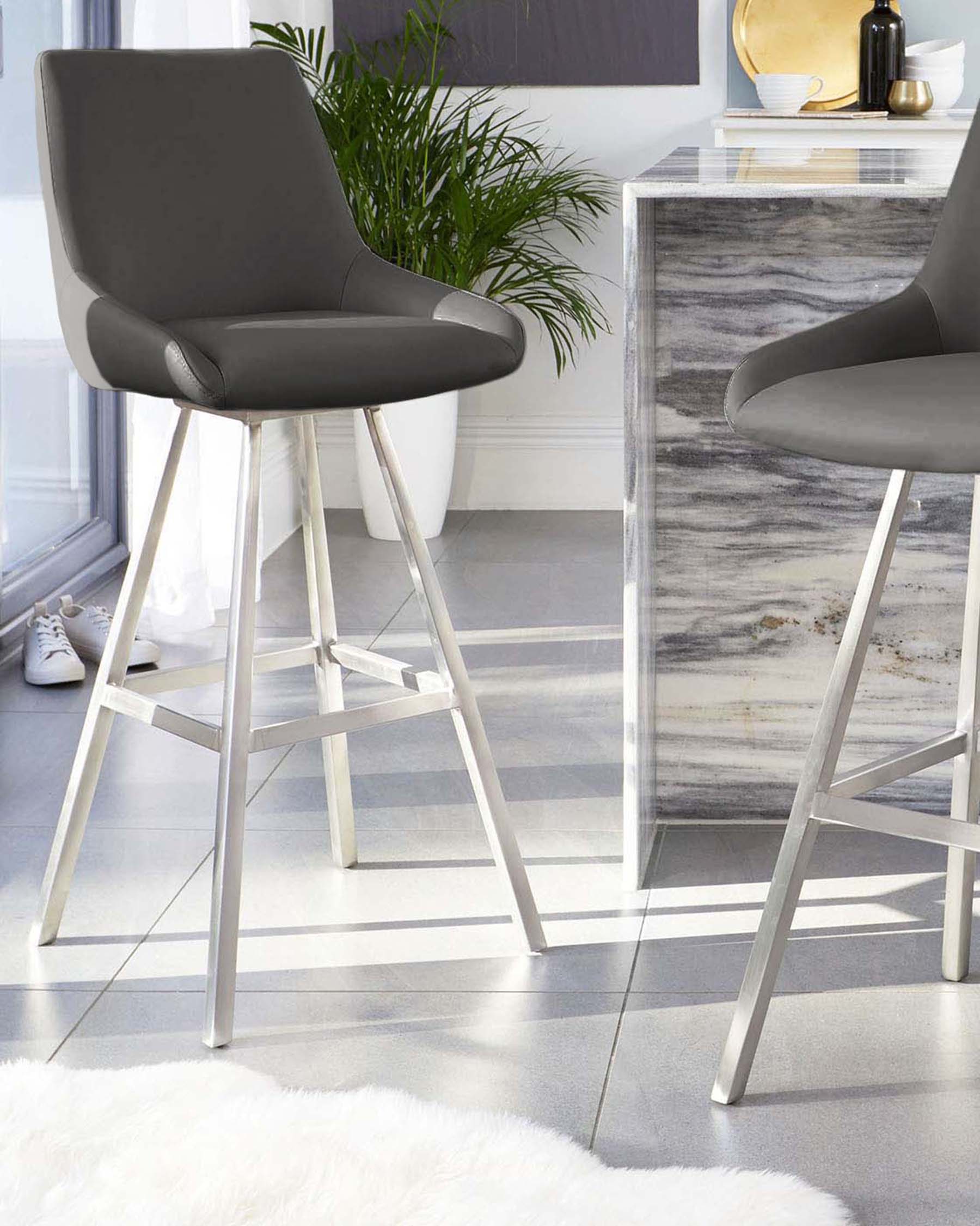 Modern bar stool with a dark grey upholstered seat and a high back on a minimalist white metal frame with angular legs and footrest. A sleek high-gloss console table with a marbled grey surface completes the elegant duo.