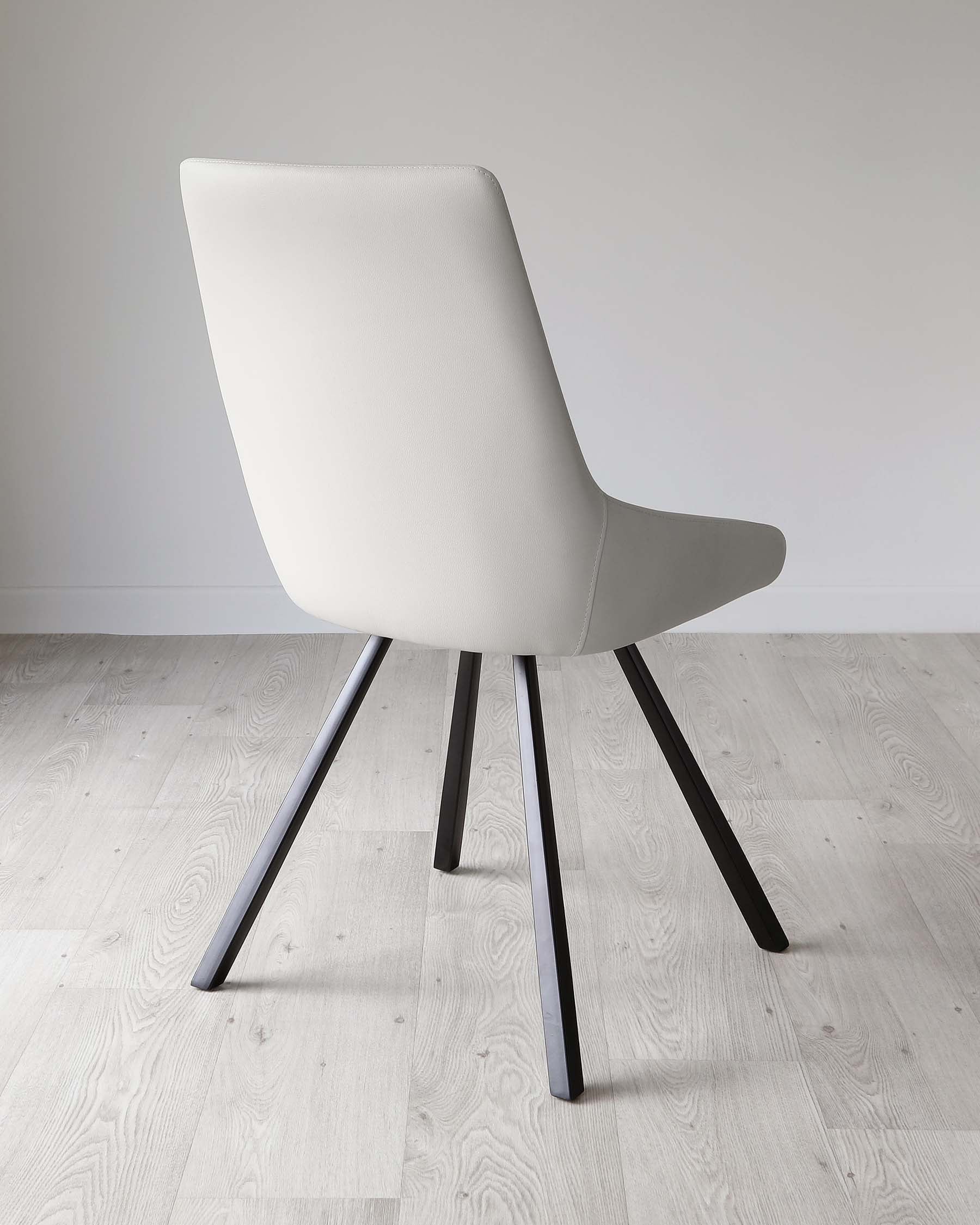 Modern light grey upholstered chair with a curved backrest and a minimalist design, featuring four angled matte black metal legs. Set on a light wood floor against a clean white wall.