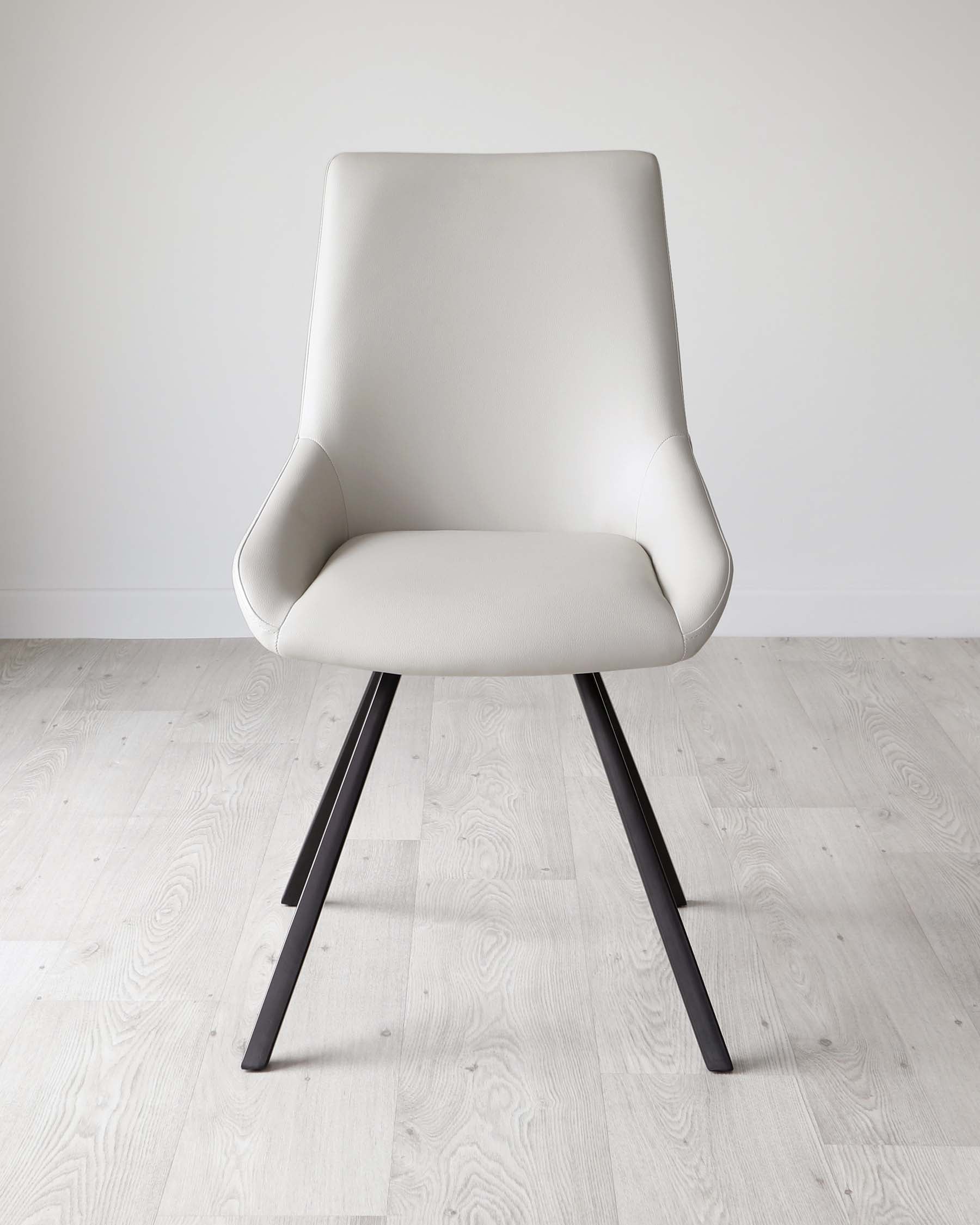 Modern light beige upholstered dining chair with a cushioned seat and backrest, featuring a curved silhouette and dark angular metal legs, set on a light wooden floor against a white wall.