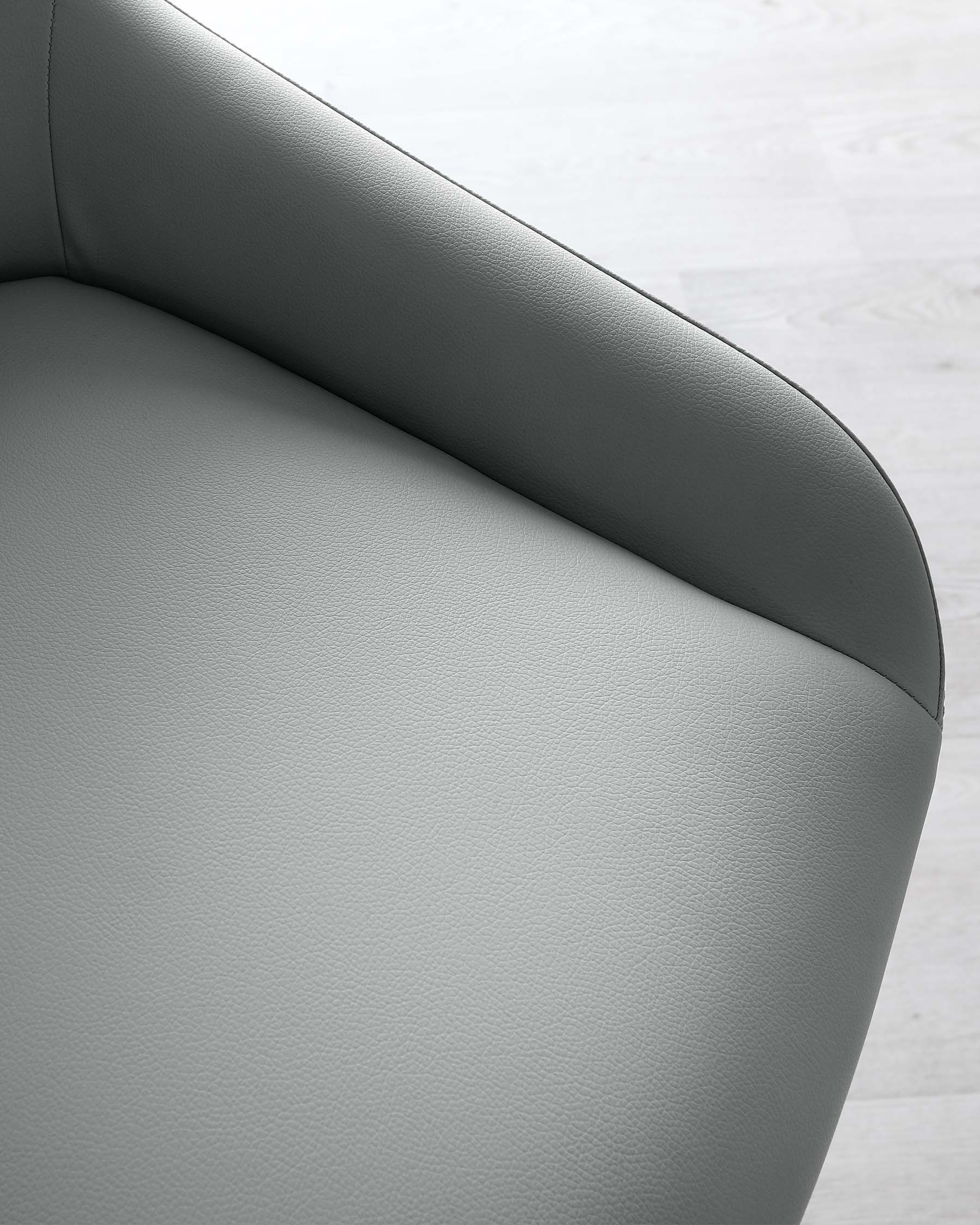 Close-up view of a modern grey upholstered chair with a curved backrest and seat design, featuring a smooth textured finish, on a light hardwood floor.