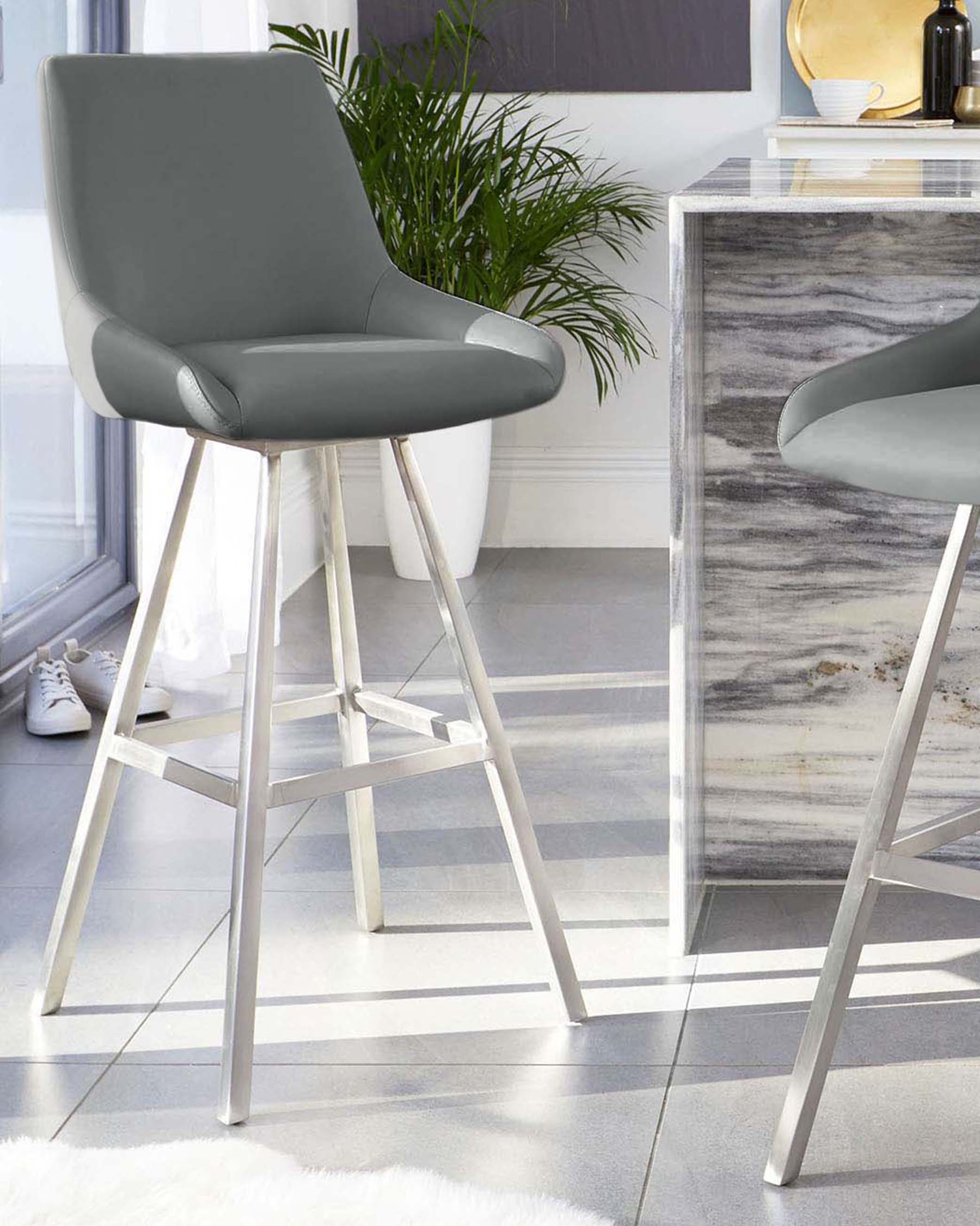 Modern grey upholstered bar stools with sleek white metal legs against a marble topped bar table.