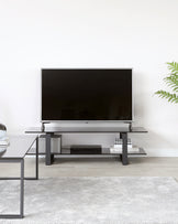 Modern minimalist TV stand in black with a multi-level, geometric design featuring open shelving.