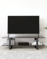 Modern minimalist TV stand featuring a dual-level design with sleek, rectangular shapes and a matte finish. The lower tier includes two horizontally elongated shelves, perfect for housing electronic devices such as a DVD player and gaming console, while the upper level provides a wider platform for the television. The unit is supported by a central column and perpendicular feet, showcasing a clean and symmetrical aesthetic.