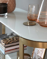 Elegant round white-topped side table with sleek gold metal legs, featuring a modern minimalist design.