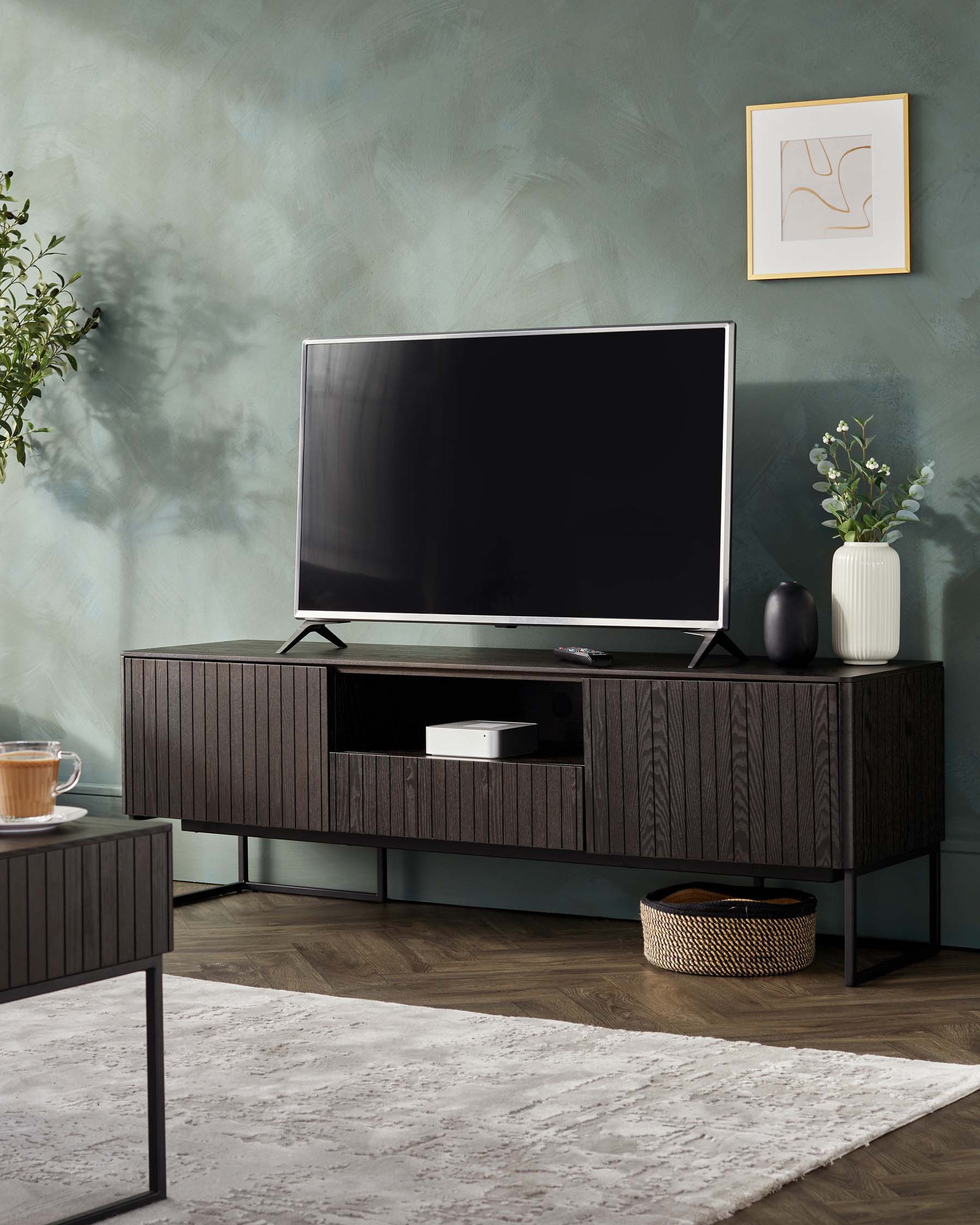 A sleek, dark wood TV stand with vertical grooves, metal legs, and ample storage, complemented by a side table and decorative plants.