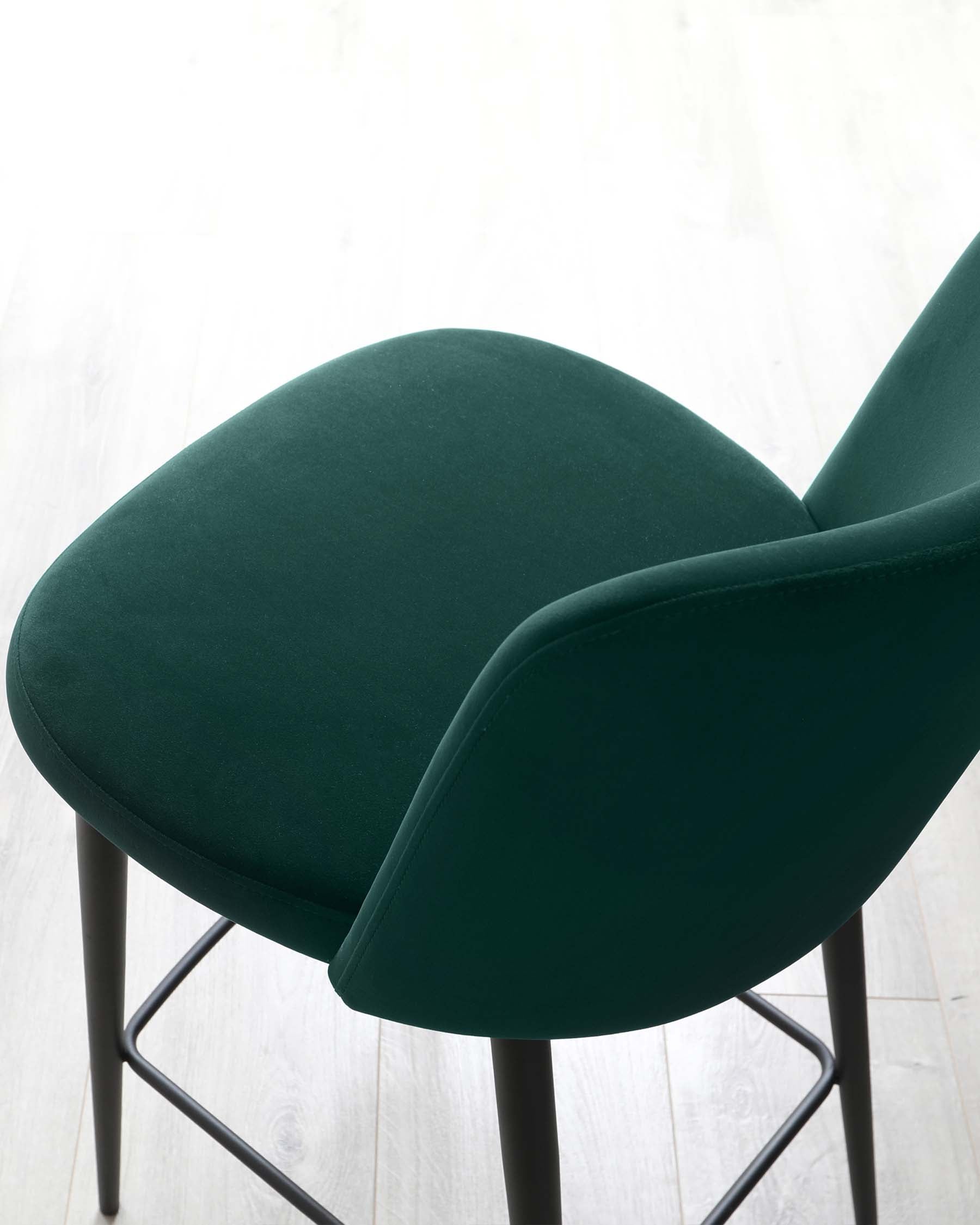 Modern dark green upholstered dining chair with a smooth, curved backrest and comfortable seat on a sleek black metal frame.