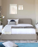 Modern minimalist bedroom with a king-sized bed featuring a grey upholstered headboard and a matching base. Bed is dressed with white linens, a striped black and white throw, and a mix of white and navy blue pillows. Flanking the bed are two white nightstands, each with a drawer and an open shelf, holding a white lamp and decorative items. A plush grey area rug is partially visible under the bed, enhancing the serene ambiance.